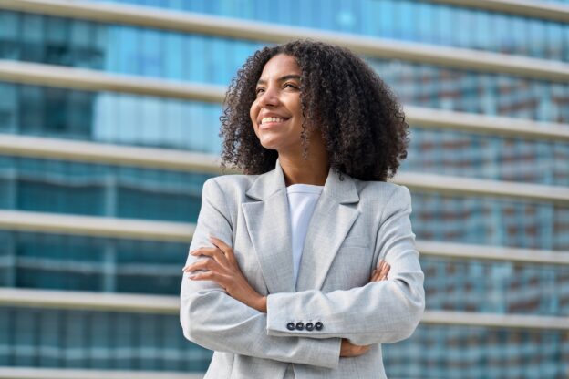 Vrouw glimlachend, denkend aan haar werkplezier en de voldoening die ze uit haar baan haalt